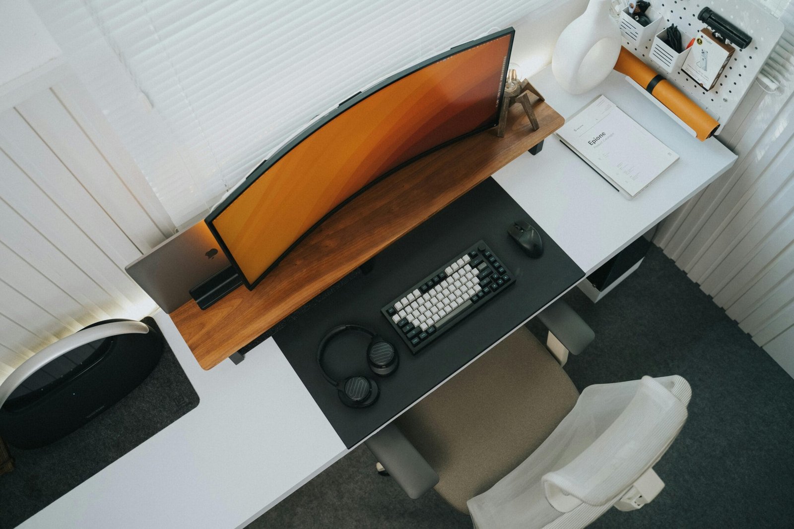 Top view of a minimalist workspace with a curved monitor, keyboard, mouse, and organized desk accessories.